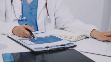 close up doctor writing notes on notebook in office