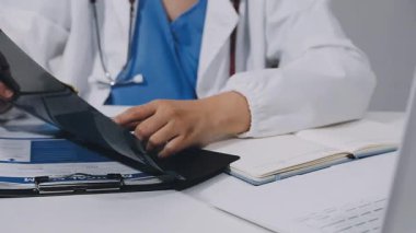 close - up of doctor holding clipboard and writing on paper