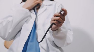 Doktor steteskop tutuyor ve kameraya bakıyor..