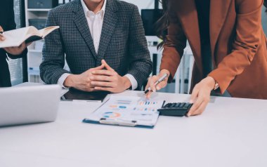 Muhasebe şirketi kazançlı nakit akışı için finansman ve vergilendirme planlaması, ofiste çalışan denetçi ve muhasebeci ekibi, mali verileri ve muhasebe kayıtlarını hesap makinesiyle analiz eder.