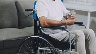 Elinde bir şişe su olan engelli bir adam.