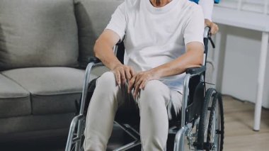 Evde tekerlekli sandalyede sakat bir adam var.