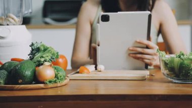 Evde salata pişirirken tablet kullanan kadın.