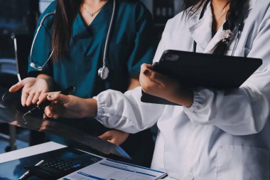 Hastane konferans salonunda kıdemli hekimin sunumu ve sağlık uygulamaları üzerine profesyonel eğitim oturumuna katılan bir grup doktor