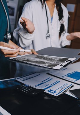 Hastane konferans salonunda kıdemli hekimin sunumu ve sağlık uygulamaları üzerine profesyonel eğitim oturumuna katılan bir grup doktor