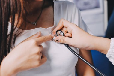 Doktor hastane yatağında steteskoplu bir hastayı muayene ediyor. Klinik ortamda tıbbi bakım ve sağlık konsepti.