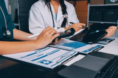 Hastane konferans salonunda kıdemli hekimin sunumu ve sağlık uygulamaları üzerine profesyonel eğitim oturumuna katılan bir grup doktor