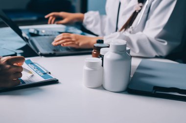 Hastane konferans salonunda kıdemli hekimin sunumu ve sağlık uygulamaları üzerine profesyonel eğitim oturumuna katılan bir grup doktor