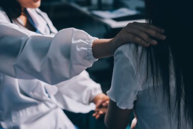 Doktor umut veriyor. Genç kadın hekimin avuçlarında elini tutan yaşlı bayanın gülümsemesini yakından çek. Beyaz önlüklü kadın bakıcı yaşlı insanı cesaretlendiriyor.