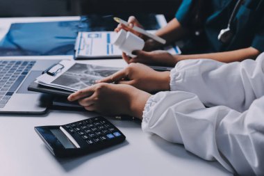 Hastane konferans salonunda kıdemli hekimin sunumu ve sağlık uygulamaları üzerine profesyonel eğitim oturumuna katılan bir grup doktor