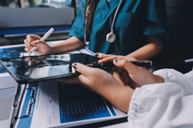 Hastane konferans salonunda kıdemli hekimin sunumu ve sağlık uygulamaları üzerine profesyonel eğitim oturumuna katılan bir grup doktor