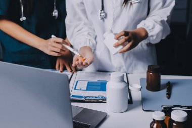 Hastane konferans salonunda kıdemli hekimin sunumu ve sağlık uygulamaları üzerine profesyonel eğitim oturumuna katılan bir grup doktor