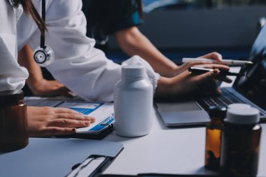 Hastane konferans salonunda kıdemli hekimin sunumu ve sağlık uygulamaları üzerine profesyonel eğitim oturumuna katılan bir grup doktor