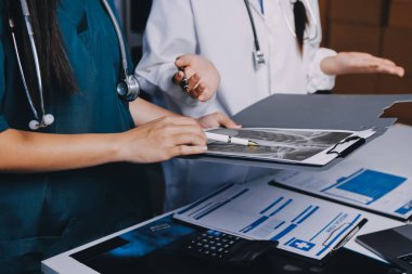 Hastane konferans salonunda kıdemli hekimin sunumu ve sağlık uygulamaları üzerine profesyonel eğitim oturumuna katılan bir grup doktor