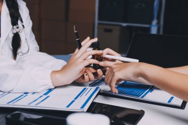 Hastane konferans salonunda kıdemli hekimin sunumu ve sağlık uygulamaları üzerine profesyonel eğitim oturumuna katılan bir grup doktor