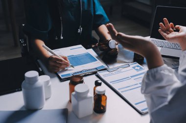 Hastane konferans salonunda kıdemli hekimin sunumu ve sağlık uygulamaları üzerine profesyonel eğitim oturumuna katılan bir grup doktor