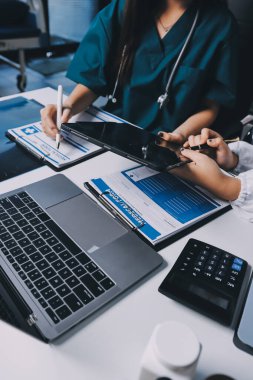 Hastane konferans salonunda kıdemli hekimin sunumu ve sağlık uygulamaları üzerine profesyonel eğitim oturumuna katılan bir grup doktor