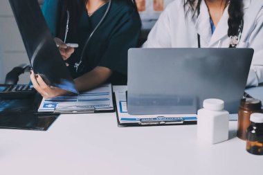 Hastane konferans salonunda kıdemli hekimin sunumu ve sağlık uygulamaları üzerine profesyonel eğitim oturumuna katılan bir grup doktor