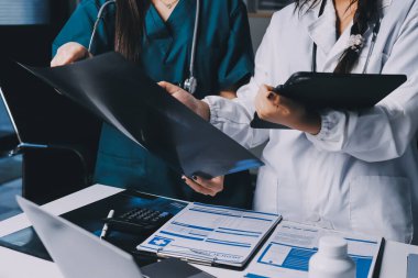 Hastane konferans salonunda kıdemli hekimin sunumu ve sağlık uygulamaları üzerine profesyonel eğitim oturumuna katılan bir grup doktor