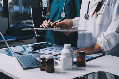 Hastane konferans salonunda kıdemli hekimin sunumu ve sağlık uygulamaları üzerine profesyonel eğitim oturumuna katılan bir grup doktor