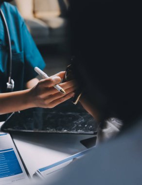 Hastane konferans salonunda kıdemli hekimin sunumu ve sağlık uygulamaları üzerine profesyonel eğitim oturumuna katılan bir grup doktor