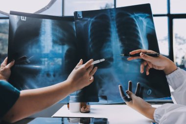 Hastane konferans salonunda kıdemli hekimin sunumu ve sağlık uygulamaları üzerine profesyonel eğitim oturumuna katılan bir grup doktor