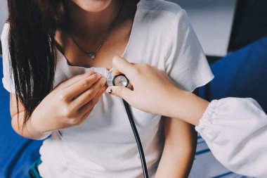 Doktor hastane yatağında steteskoplu bir hastayı muayene ediyor. Klinik ortamda tıbbi bakım ve sağlık konsepti.