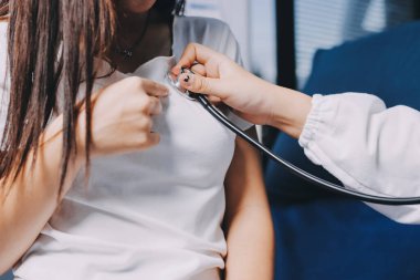 Doktor hastane yatağında steteskoplu bir hastayı muayene ediyor. Klinik ortamda tıbbi bakım ve sağlık konsepti.