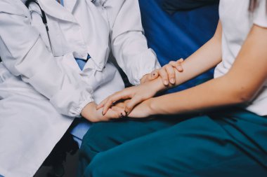 Doktor umut veriyor. Genç kadın hekimin avuçlarında elini tutan yaşlı bayanın gülümsemesini yakından çek. Beyaz önlüklü kadın bakıcı yaşlı insanı cesaretlendiriyor.