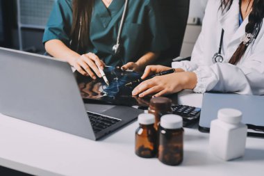 Hastane konferans salonunda kıdemli hekimin sunumu ve sağlık uygulamaları üzerine profesyonel eğitim oturumuna katılan bir grup doktor