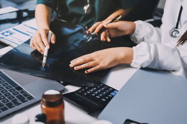 Hastane konferans salonunda kıdemli hekimin sunumu ve sağlık uygulamaları üzerine profesyonel eğitim oturumuna katılan bir grup doktor