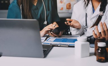 Hastane konferans salonunda kıdemli hekimin sunumu ve sağlık uygulamaları üzerine profesyonel eğitim oturumuna katılan bir grup doktor