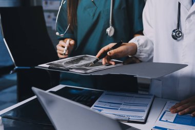 Hastane konferans salonunda kıdemli hekimin sunumu ve sağlık uygulamaları üzerine profesyonel eğitim oturumuna katılan bir grup doktor