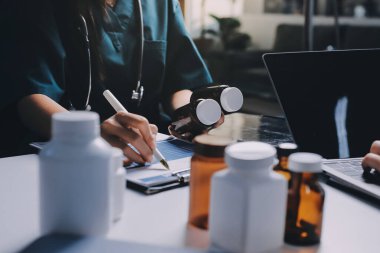 Hastane konferans salonunda kıdemli hekimin sunumu ve sağlık uygulamaları üzerine profesyonel eğitim oturumuna katılan bir grup doktor