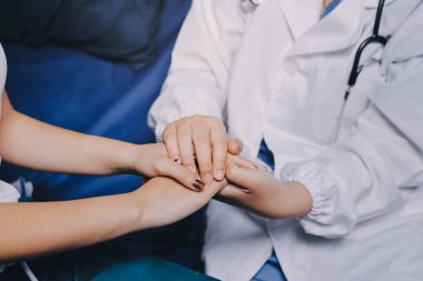 Doktor umut veriyor. Genç kadın hekimin avuçlarında elini tutan yaşlı bayanın gülümsemesini yakından çek. Beyaz önlüklü kadın bakıcı yaşlı insanı cesaretlendiriyor.