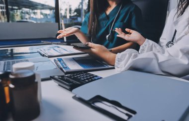 Hastane konferans salonunda kıdemli hekimin sunumu ve sağlık uygulamaları üzerine profesyonel eğitim oturumuna katılan bir grup doktor