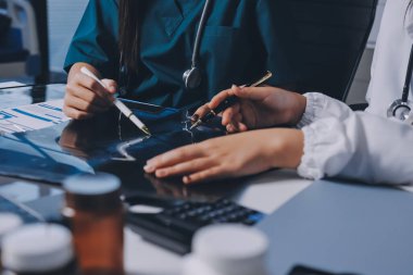 Hastane konferans salonunda kıdemli hekimin sunumu ve sağlık uygulamaları üzerine profesyonel eğitim oturumuna katılan bir grup doktor