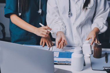 Hastane konferans salonunda kıdemli hekimin sunumu ve sağlık uygulamaları üzerine profesyonel eğitim oturumuna katılan bir grup doktor