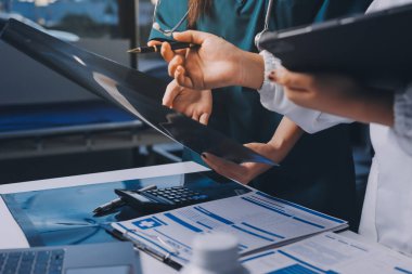 Hastane konferans salonunda kıdemli hekimin sunumu ve sağlık uygulamaları üzerine profesyonel eğitim oturumuna katılan bir grup doktor