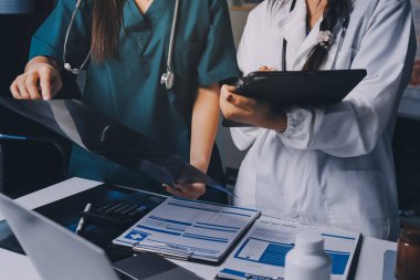 Hastane konferans salonunda kıdemli hekimin sunumu ve sağlık uygulamaları üzerine profesyonel eğitim oturumuna katılan bir grup doktor