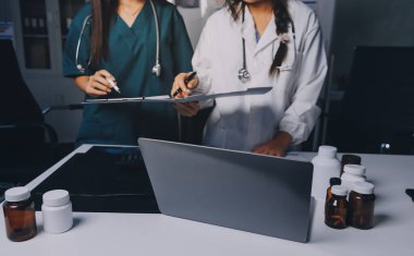 Hastane konferans salonunda kıdemli hekimin sunumu ve sağlık uygulamaları üzerine profesyonel eğitim oturumuna katılan bir grup doktor