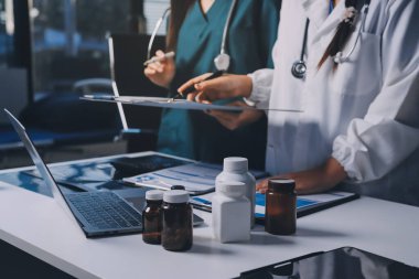 Hastane konferans salonunda kıdemli hekimin sunumu ve sağlık uygulamaları üzerine profesyonel eğitim oturumuna katılan bir grup doktor