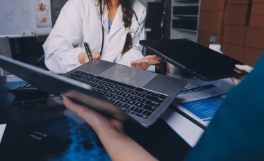 Hastane konferans salonunda kıdemli hekimin sunumu ve sağlık uygulamaları üzerine profesyonel eğitim oturumuna katılan bir grup doktor