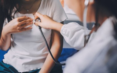 Doktor hastane yatağında steteskoplu bir hastayı muayene ediyor. Klinik ortamda tıbbi bakım ve sağlık konsepti.