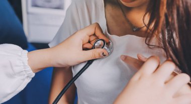 Doktor hastane yatağında steteskoplu bir hastayı muayene ediyor. Klinik ortamda tıbbi bakım ve sağlık konsepti.