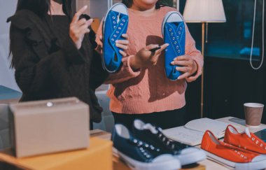 Asyalı bir kadın, sosyal ağda canlı yayında kıyafet satmayı sosyal medyada kıyafet satmayı anlatıyor. Blogger kadın nüfuzlu, KME perakende mağazası sahibi.