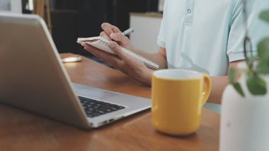 İki finans muhasebecisi dizüstü bilgisayardaki iş tablolarını analiz ediyor, ofis masasında oturuyor, kağıt belgelerine bakıyor, veri tabanlarıyla çalışan hesap makinesi kullanıyor, üstün tabloları kontrol ediyor.