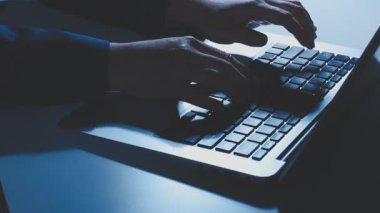 Bir adamın elleri geceleri dizüstü bilgisayarda klavye yazmakla meşguldür. İşle, iş geliştirmeyle, çalışmayla ve bilgisayar oyunları oynamakla meşguldür.