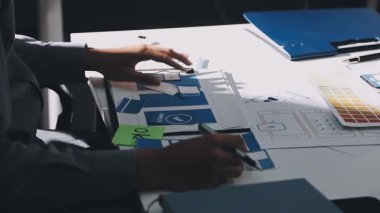 Uxui tasarımcılarından oluşan bir ekip bilgisayar ekranını işaret ederek ofiste yeni mobil uygulama tasarımını tartışıyor.