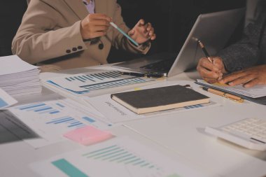 Tablet, akıllı telefon ve dizüstü bilgisayarlı iş belgeleri ve veri tartışan iki iş arkadaşı